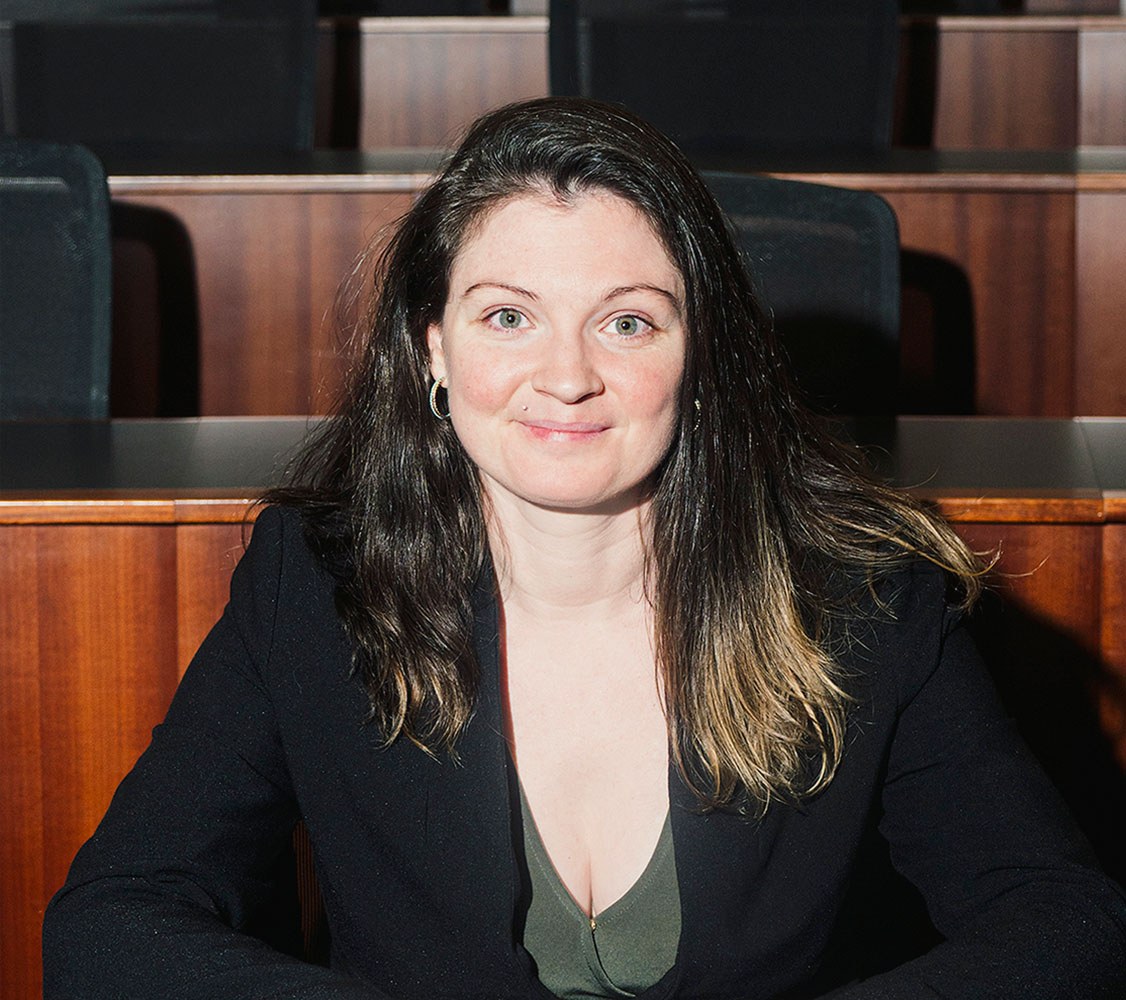 Portrait of Christine DeMaria smiling, in a library