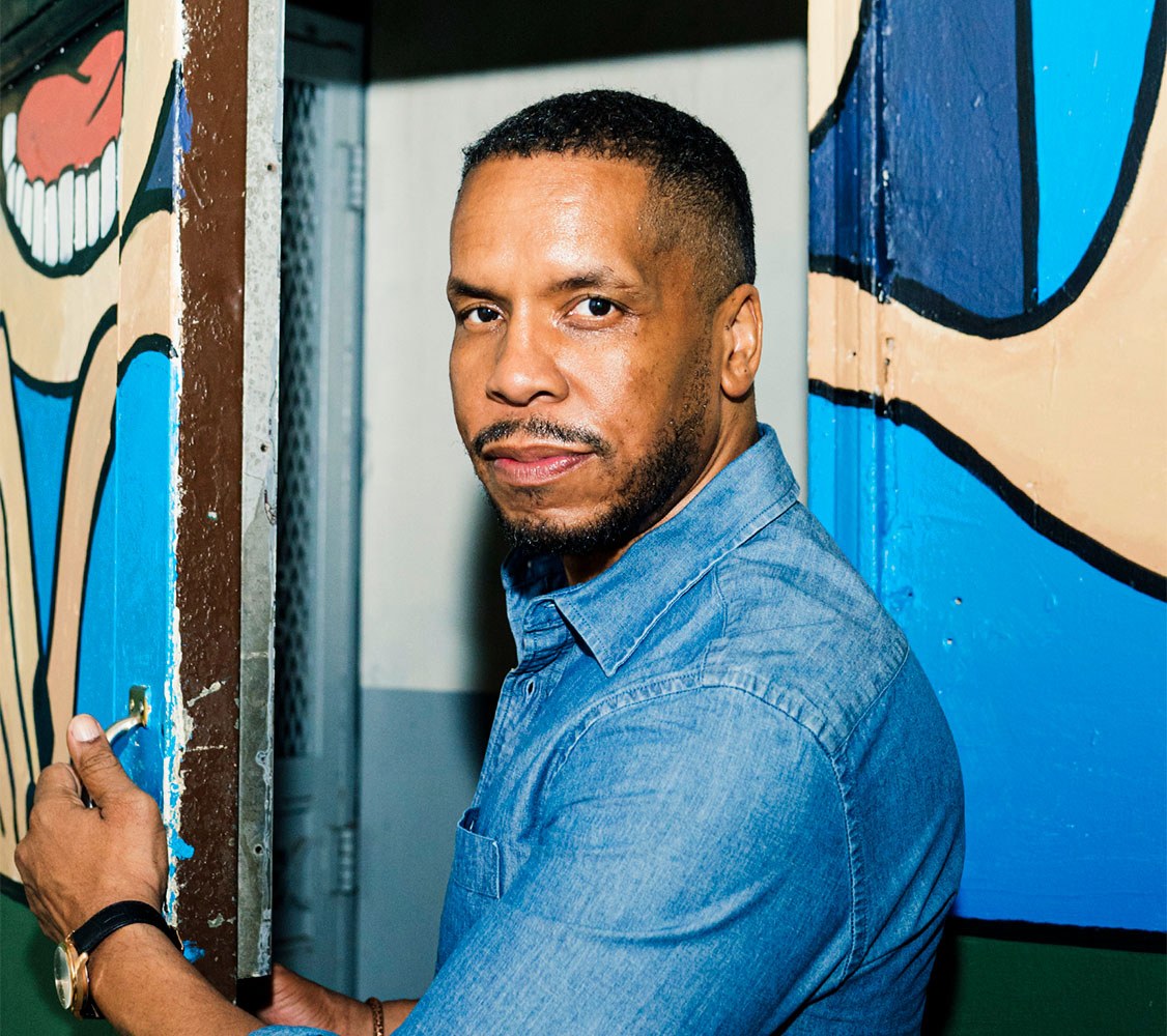 Portrait of Gregory Purnell in front of a wall with colorful illustrations