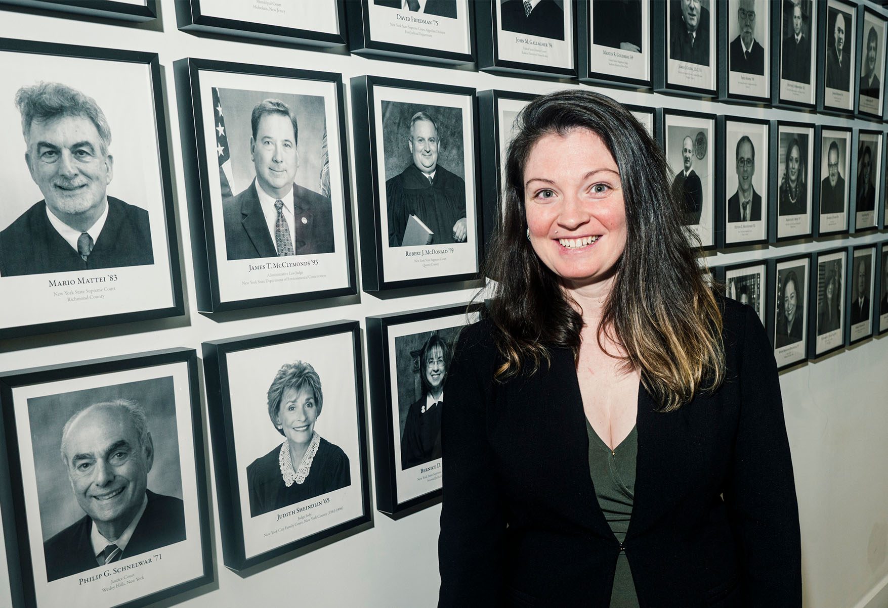 Christine DeMaria standing in front of a wall of photos.