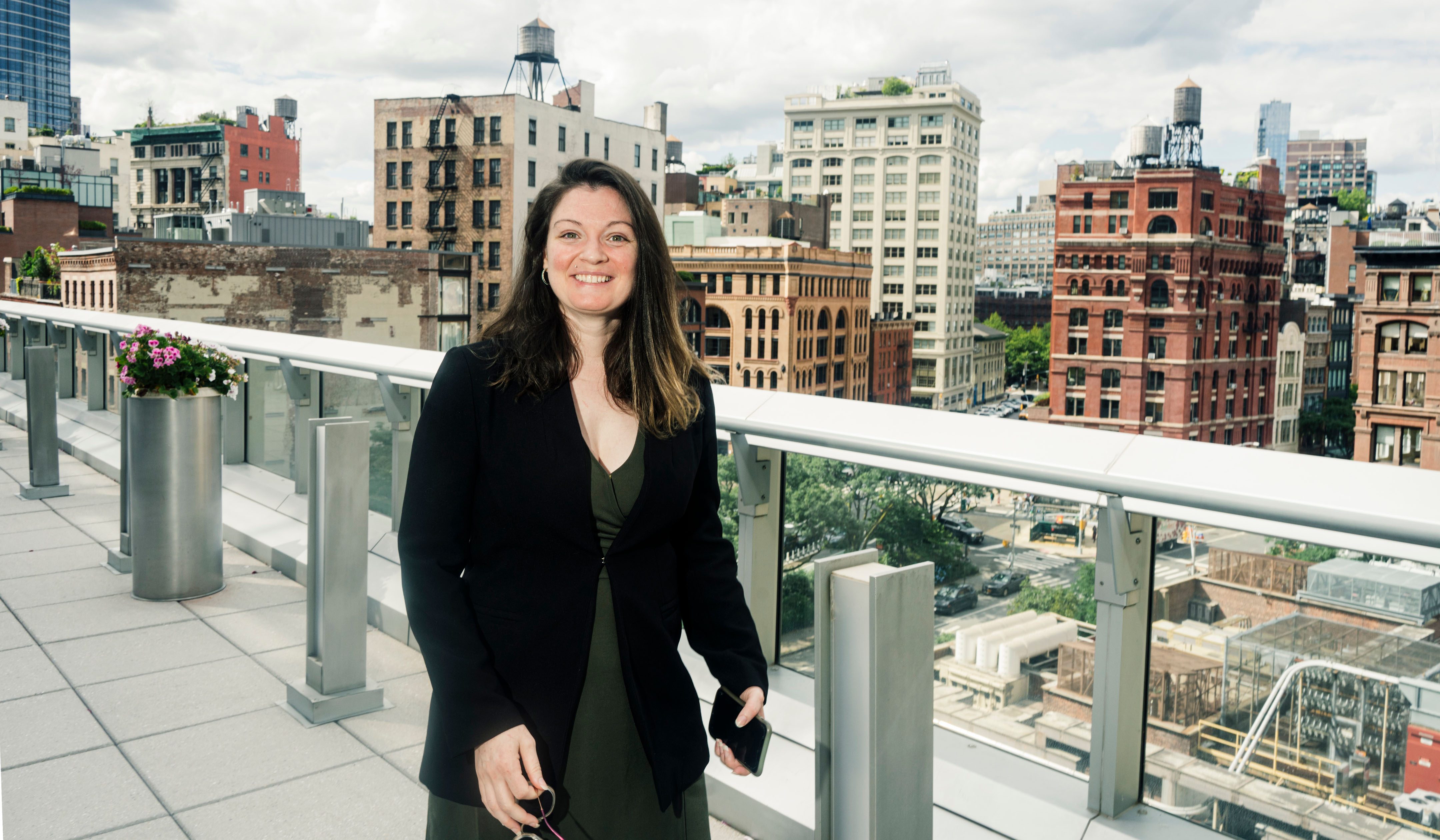 Christine DeMaria on a rooftop. In the background is a skyline of New York City's Tribeca neighborhood.