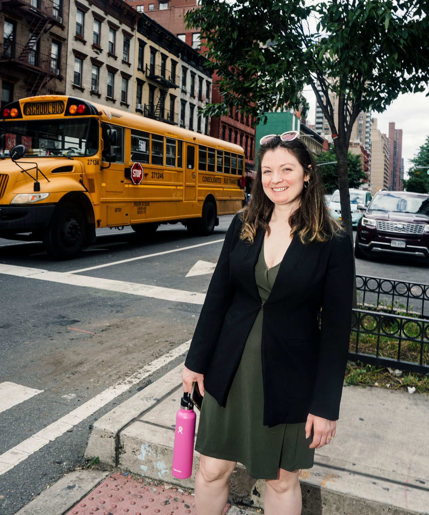 Christine DeMaria standing in the street. School bus at a traffic light in the background.