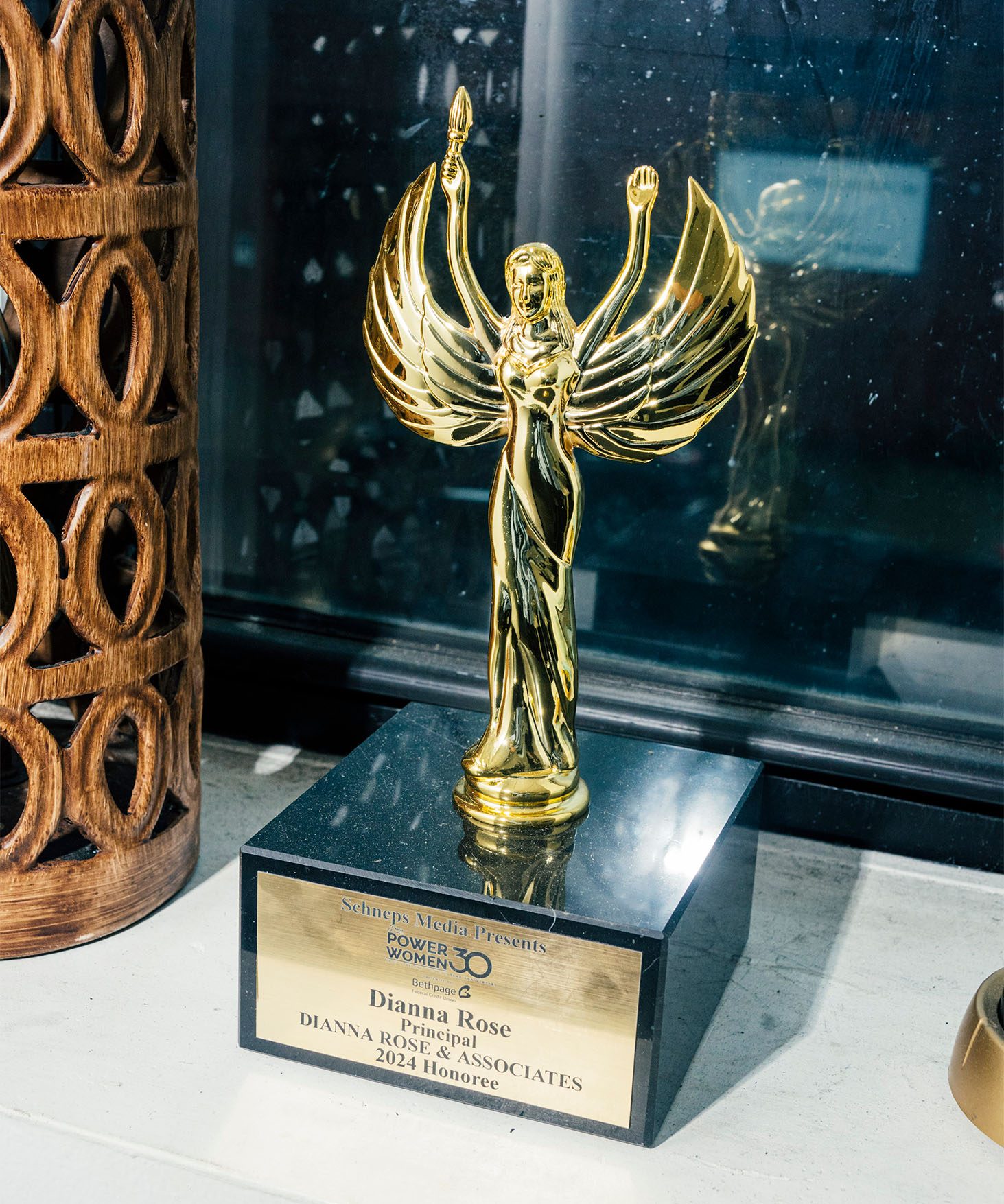 View of a golden statue with wings. On the base it reads: Schneps Media Presents “Power Women 30”— Dianna Rose — Principal — Dianna Rose & Associates — 2024 Honoree.
