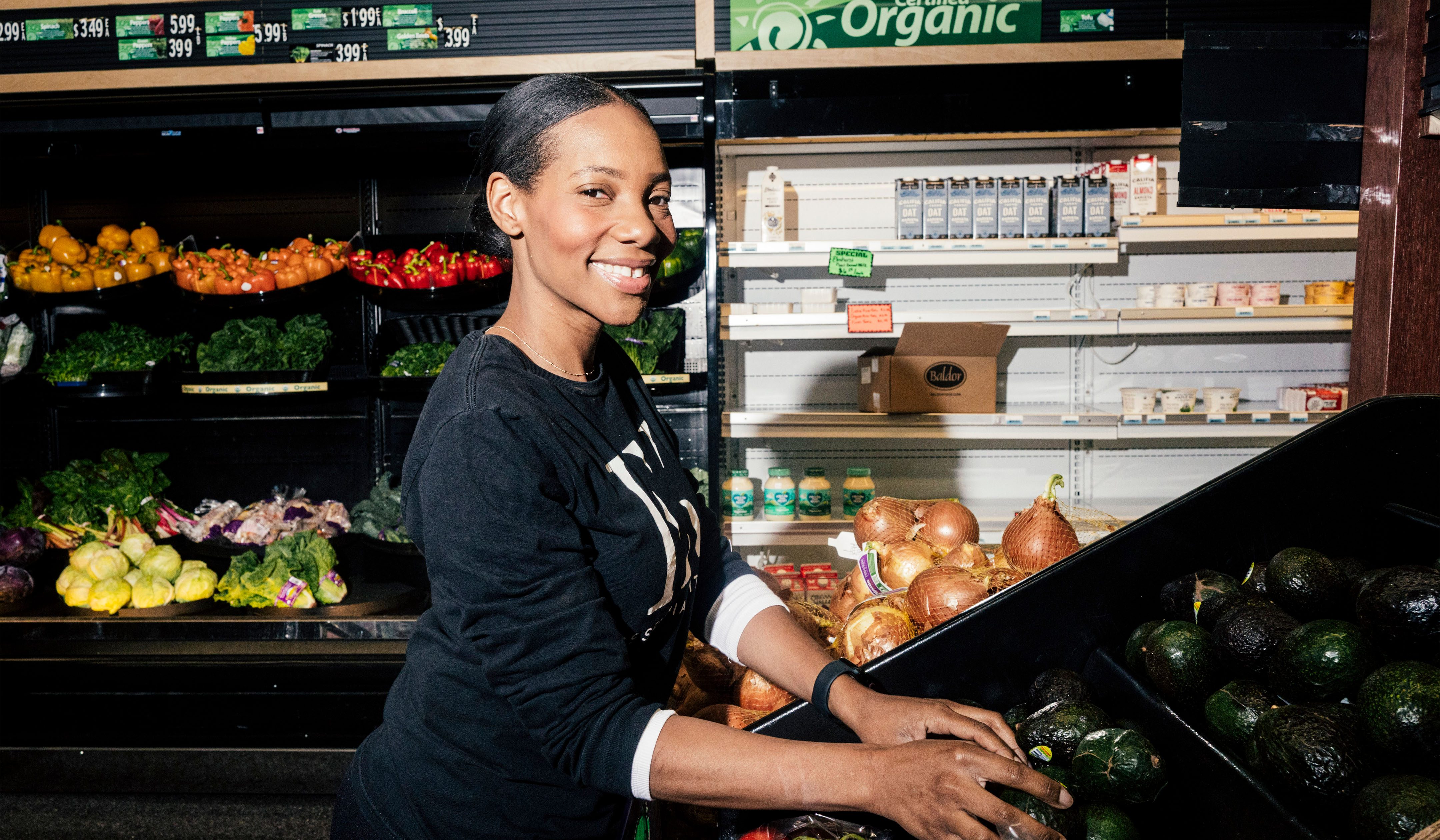 Dianna Rose smiling at a supermarket, surrounded by shelves of produce.