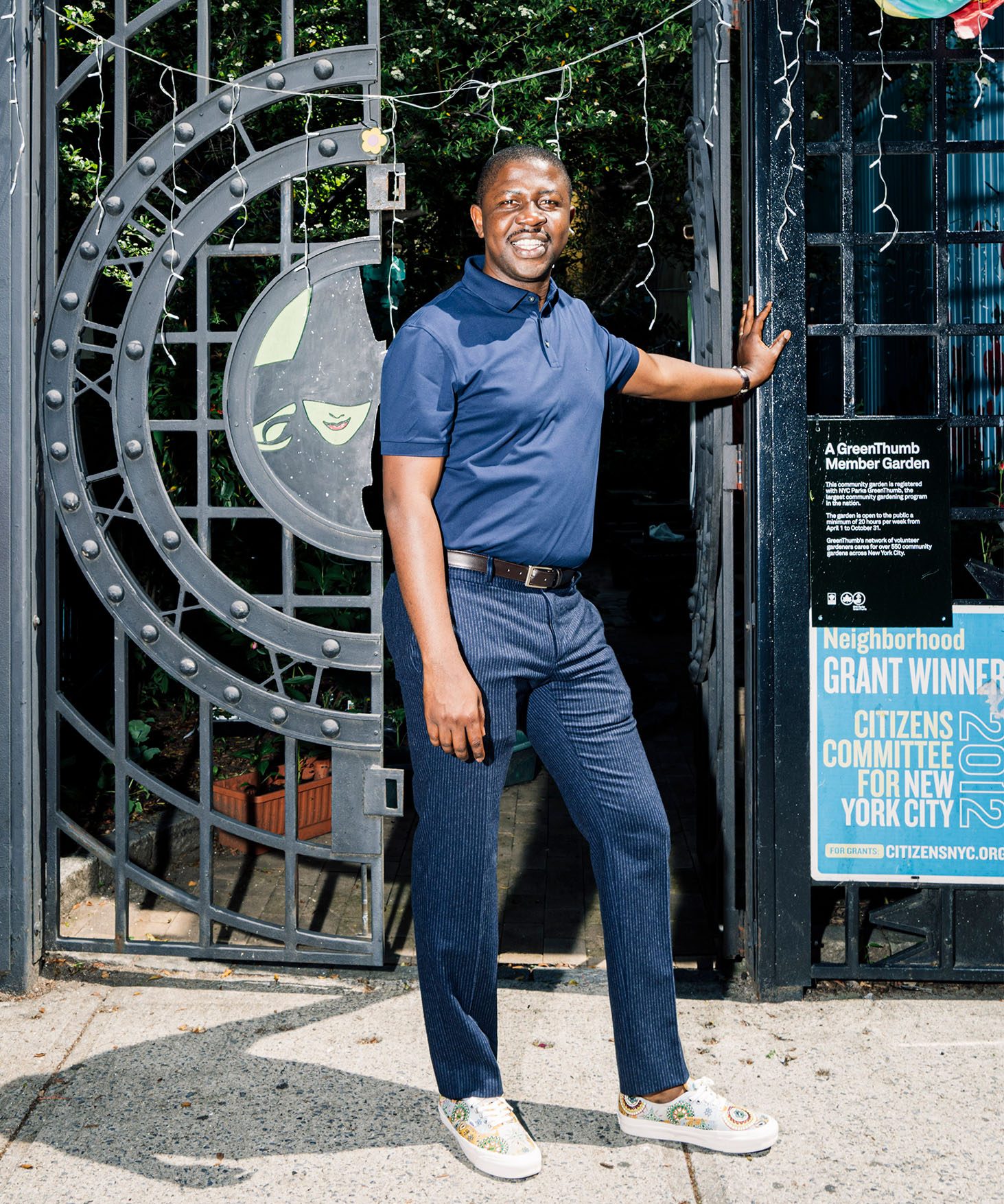 Edafe Okporo standing in front of a gate to a garden.