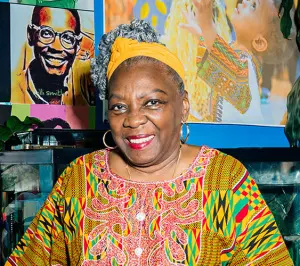 Portrait of Fela Barclift smiling in front of a wall with artwork