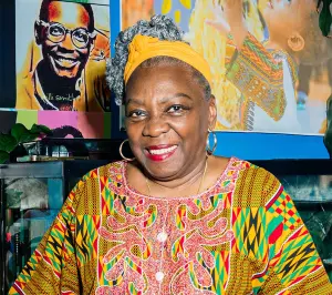 Portrait of Fela Barclift smiling in front of a wall with artwork